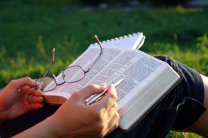 woman holding a pen over a Bible